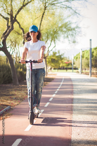 Woman riding an electric kick scooter down the bike path