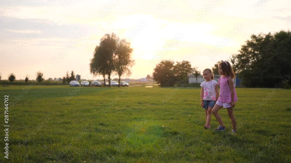 Two little girl friends outdoors play launch a toy plane on nature park sunset time Two little girl friends outdoors play launch a toy plane on nature park sunset time