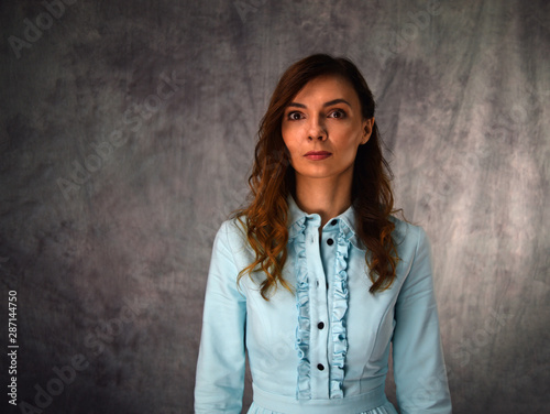 Fashion portrait of a girl in a blue dress on a gray background. © YAROSLOVEPHOTOVIDEO