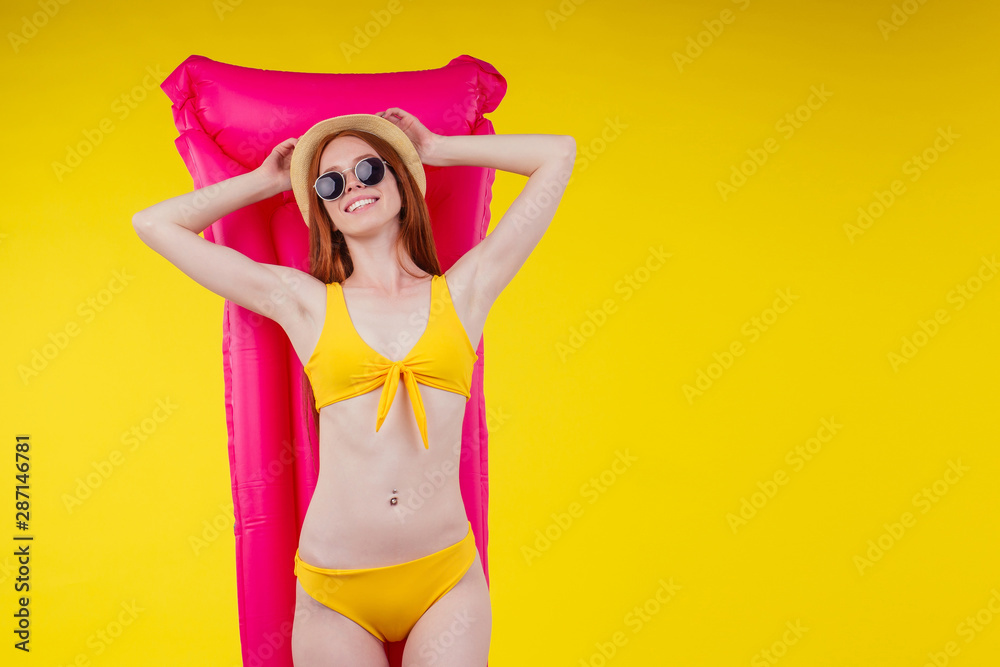 redhaired ginger female posing floating with inflatable mattress wearing swimmingsuit and hat,good looking in studio yellow background redhaired ginger female posing floating with inflatable mattress wearing swimmingsuit and hat,good looking in studio yellow background