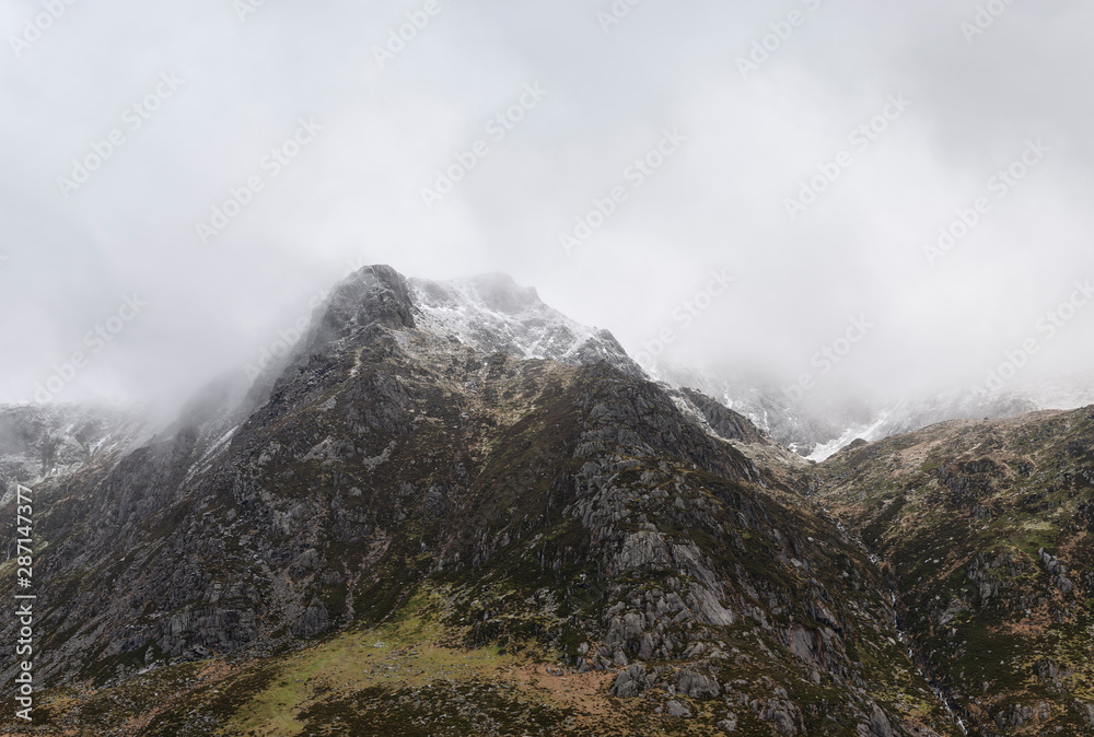 Stunning moody dramatic Winter landscape image of snowcapped Y Garn mountain in Snowdonia