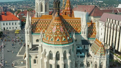 Budapest, Hungary - 4K drone flying away from the beautiful roof of Matthias Church in front of the Fisherman's Bastion at the heart of Buda's Castle District on a bright summer day