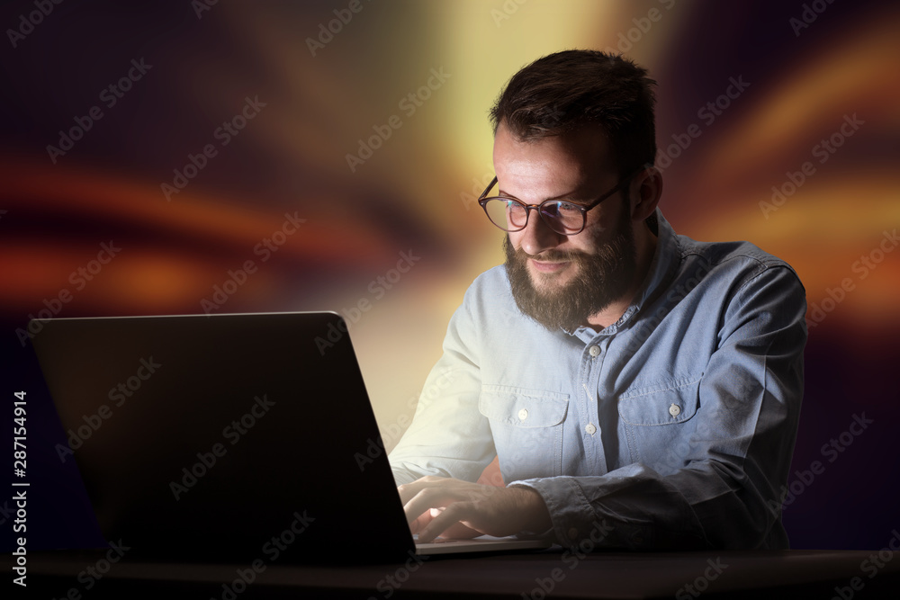 Young handsome businessman working late at night in the office with warm lights in the background Young handsome businessman working late at night in the office with warm lights in the background