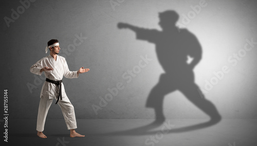 Young karate man confronting with his own shadow