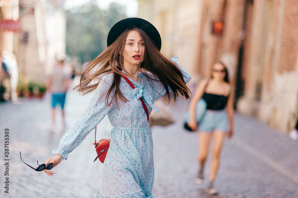 Elegant stylish lady in blue dress and hat looking back with emotional face on street Elegant stylish lady in blue dress and hat looking back with emotional face on street