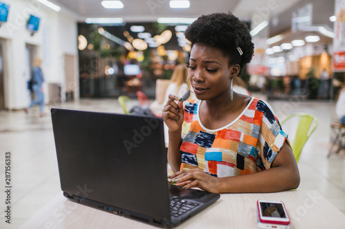 Beautiful Young Dark Skinned Freelancer Woman Using Laptop Computer Sitting At Cafe Table.  Freelance Work Concept. photo