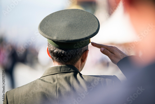 Fototapeta Commander in formal uniform salutes from backside view.