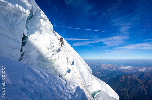 Alpinist mountaineer climbing dangerous ice crevasse crack.