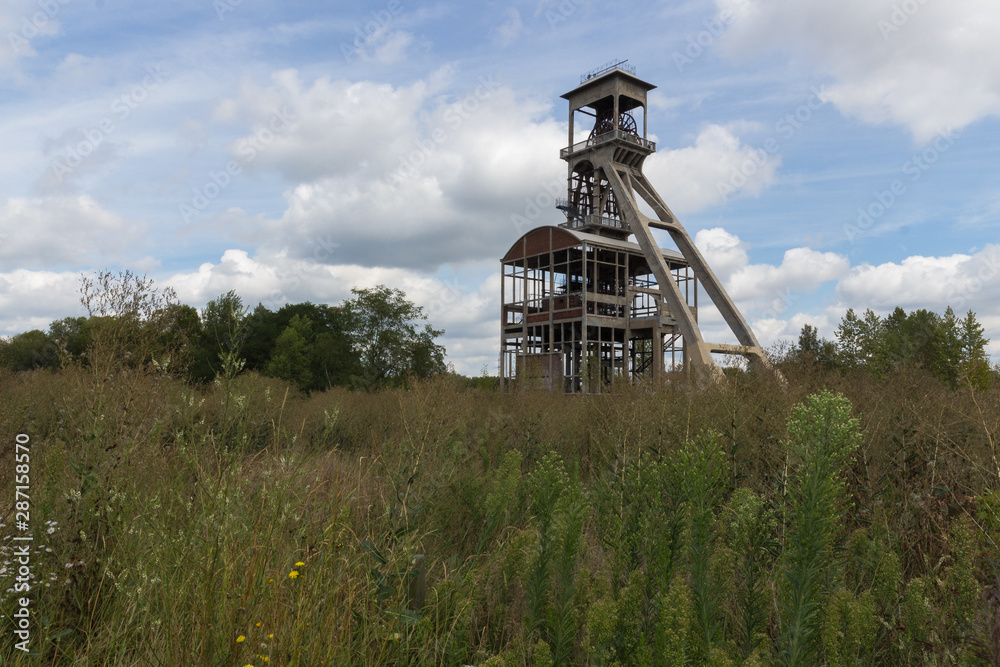 A dramatic sky with former elevator shaft for the coal mines in Maasmechelen, Belgium nowadays converted area and being part of a free public park A dramatic sky with former elevator shaft for the coal mines in Maasmechelen, Belgium nowadays converted area and being part of a free public park