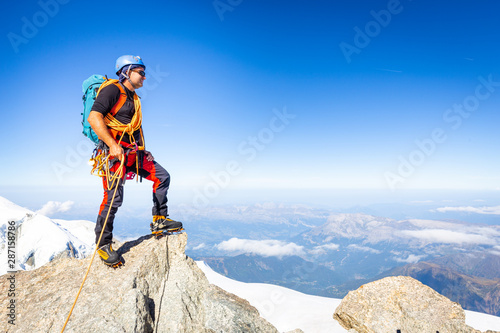 фотографія Alpinist mountaineer standing rock cliff mountain summit.