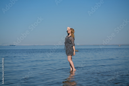 Attractive plus size woman in chiffon dress enjoys the shiny water in the blue sea