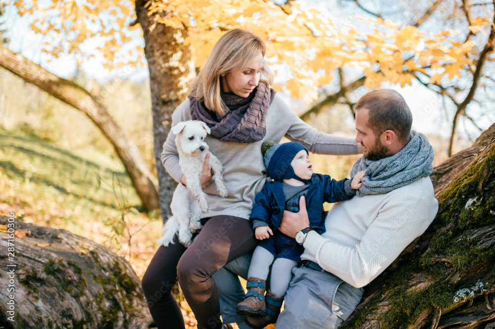 Happy family couple with their son and little puppy in autumn park Happy family couple with their son and little puppy in autumn park