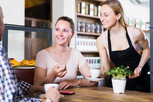 cheerful waiter girl brought cup of coffee for couple of different aged people