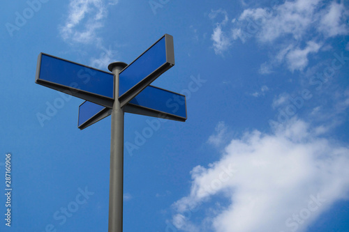 Direction road sign mock up. Real arrow form tables with blank empty space to add any text or symbols. Four destinations plates on pole to direct way or route on blue sky background
