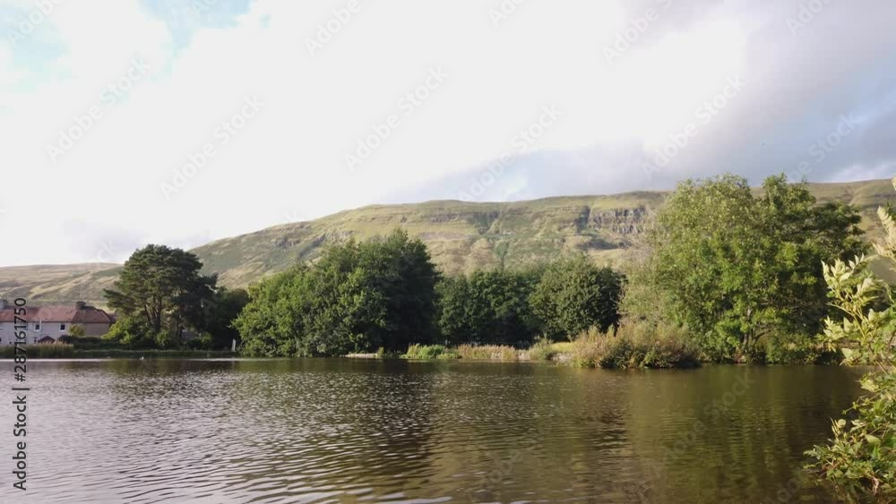 View across the rippling surface water of a rural village pond. View across the rippling surface water of a rural village pond.