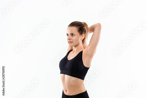 Pretty young sporty blond woman in a black sportswear stretching after exercising isolated over white background. © ianachyrva