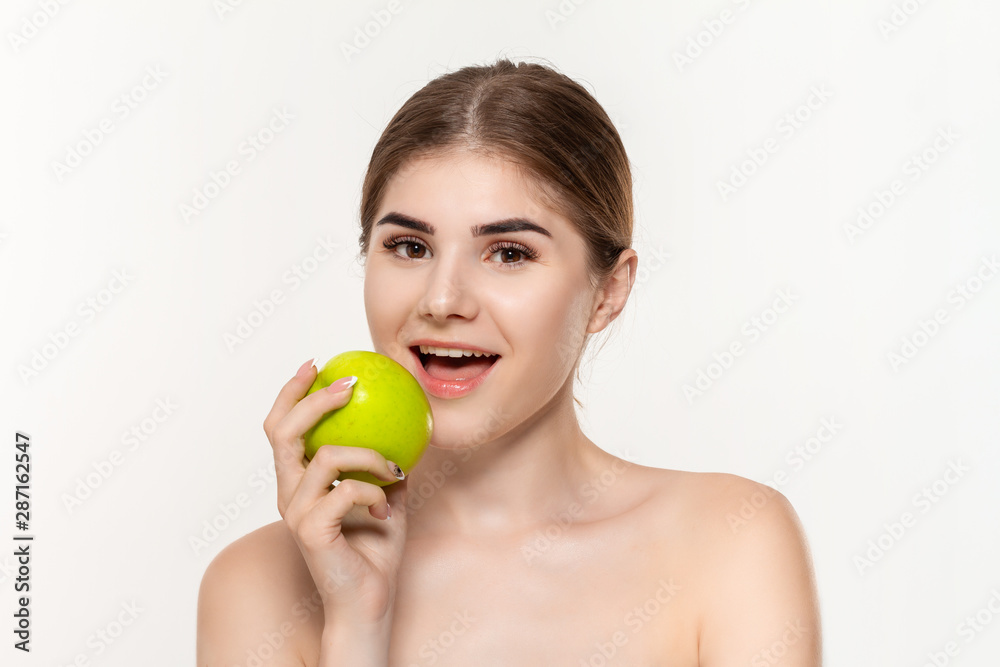 Close-up portrait of a happy beautiful young girl biting green apple isolated over white background. Concept of beauty and health care. Close-up portrait of a happy beautiful young girl biting green apple isolated over white background. Concept of beauty and health care.