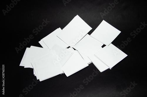 stack of white paper small squares stickers on black background © Arthur Shevtsov