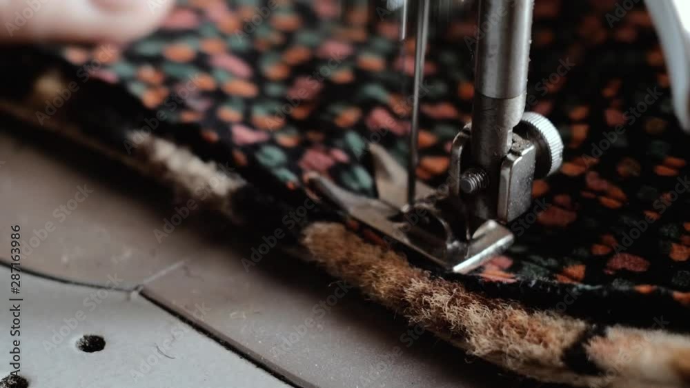 Sewing Machine Needle in Motion. Close-up of sewing machine needle rapidly moves up and down. The tailor sews fabric on the sewing workshop. The process of sewing fabric. Sewing Machine Needle in Motion. Close-up of sewing machine needle rapidly moves up and down. The tailor sews fabric on the sewing workshop. The process of sewing fabric.
