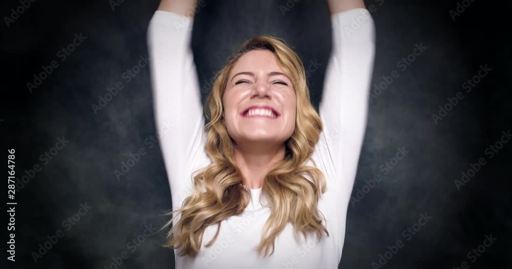 Beautiful blonde celebrates victory and rejoices on a dark background. 4K video. Beautiful blonde celebrates victory and rejoices on a dark background. 4K video.