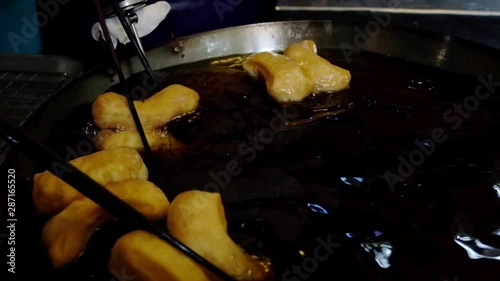 Chef making Youtiao in Hot Frying Pan in Local Market, Traditional Fried Dough Food. Chinese Cruller. Dolly Shot
