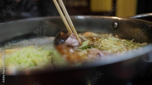 Shabu-Shabu or Sukiyaki, Japanese or Chinese Traditional Food. a Woman Dipping Sliced Pork in Hot Pot by Chopstick. Slow Motion Shot. Selective Focus