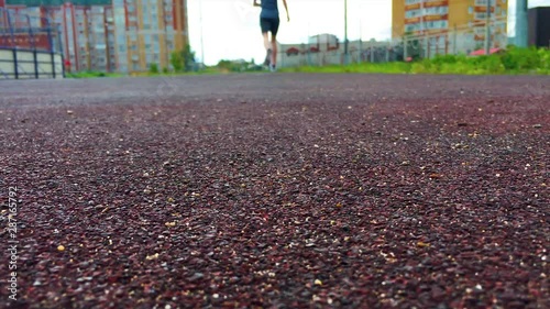A man runs through the stadium in a t-shirt, sneakers and shorts. Athlete, rear view. The movement begins abruptly, with a jump of the person in the frame. Ambitions, goals, training