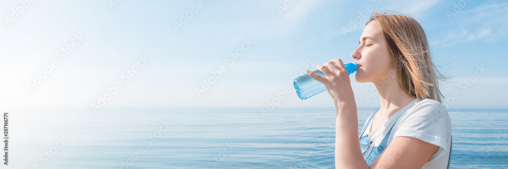Young beautiful girl drinking pure mineral water from a plastic bottle on the background of the sea landscape, panorama. Young beautiful girl drinking pure mineral water from a plastic bottle on the background of the sea landscape, panorama.