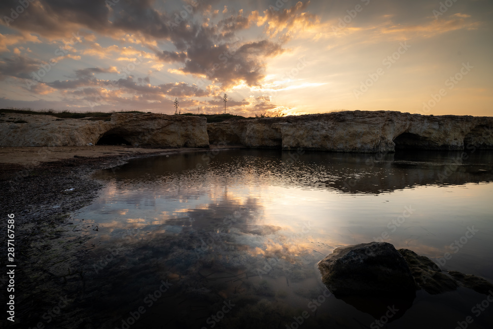 Shot of the sun rising behind the rocks at Cirica Bay at sunrise. Cirica is a beautiful nature seaside place made of cliffs, rocks and sand in the southern Sicily, Italy