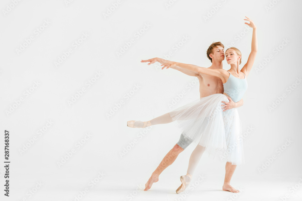 Young couple of modern ballet dancers posing over white studio background Young couple of modern ballet dancers posing over white studio background