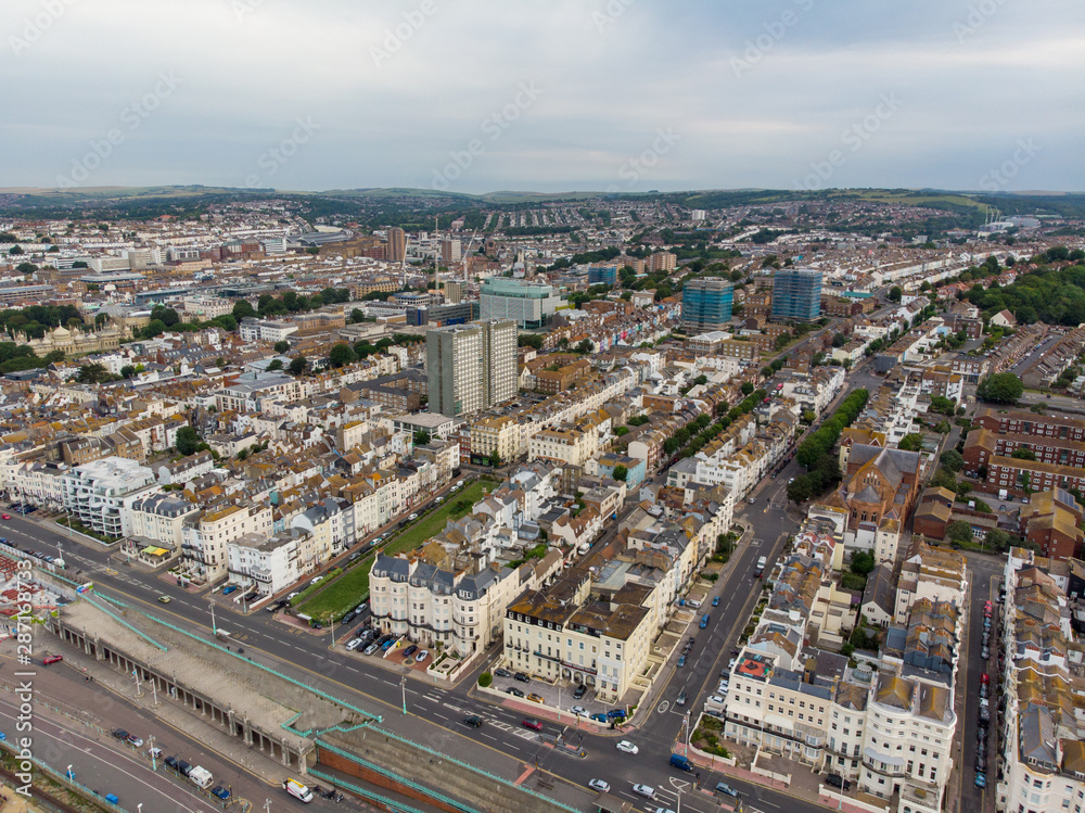 Aerial photo of the Brighton and Hove town centre showing hotels, guest houses, local businesses and the roads and streets of the town centre, taken on a bright sunny day with a drone over the town.