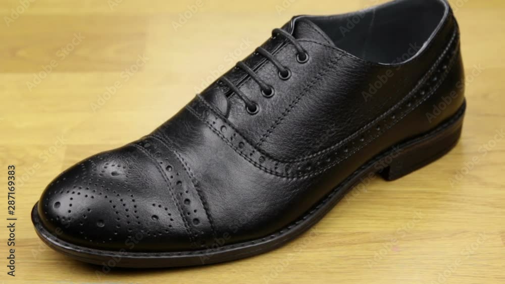 Approaching, black classic men's shoes standing on a wooden floor. Men's fashion. Approaching, black classic men's shoes standing on a wooden floor. Men's fashion.