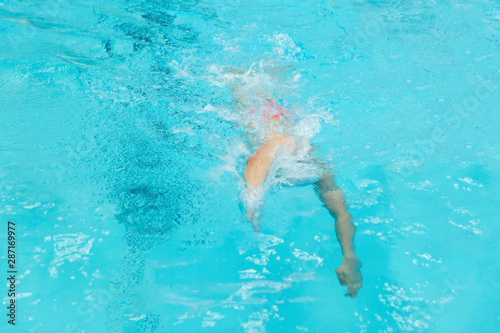 A young boy pounds in the pool.
