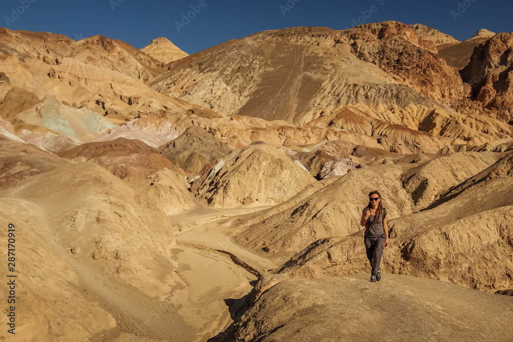 A hiker in the Artist`s Palette landmark place in Death Valley National Park, Geology, sand. A hiker in the Artist`s Palette landmark place in Death Valley National Park, Geology, sand.