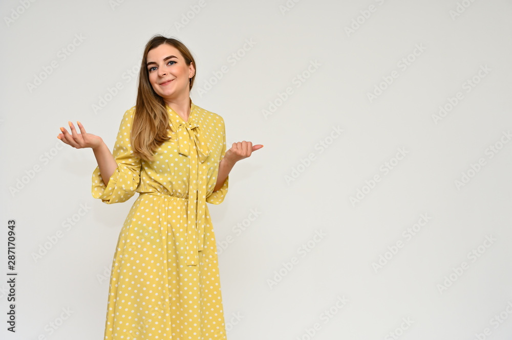 Portrait of a cute middle-aged manager brunette woman with beautiful curly hair in a yellow dress on a white background. Beauty, brightness, smile. Portrait of a cute middle-aged manager brunette woman with beautiful curly hair in a yellow dress on a white background. Beauty, brightness, smile.