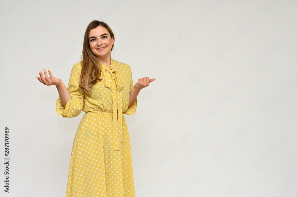 Portrait of a cute middle-aged manager brunette woman with beautiful curly hair in a yellow dress on a white background. Beauty, brightness, smile. Portrait of a cute middle-aged manager brunette woman with beautiful curly hair in a yellow dress on a white background. Beauty, brightness, smile.