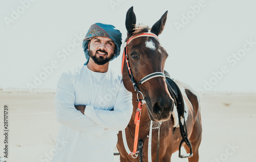 Arabian man with traditional clothes riding his horse photo