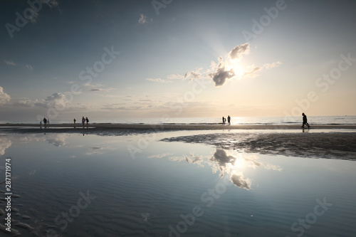 people silhouettes on sea sand beach in sunshine