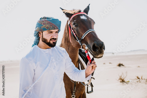 Photography Arabian man with traditional clothes riding his horse