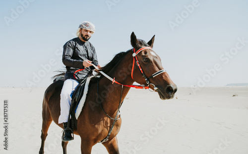 Arabian man with traditional clothes riding his horse © oneinchpunch