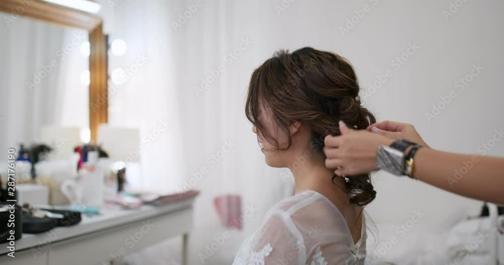 Female hairdresser standing and making hairstyle on bride in beauty salon Female hairdresser standing and making hairstyle on bride in beauty salon