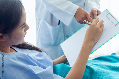 The patient, an Asian woman, is testing the writing of letters. With the right hand On white paper To test the hand senses As doctor ordered to check treatment results. In the patient’s ward.
