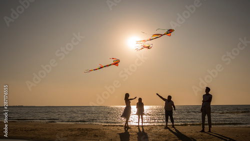 Friendly family plays with kites on the seashore.