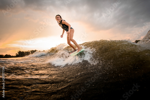 Sporty girl riding on the wakeboard on the river on the wave © fesenko