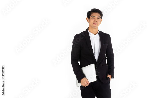 Handsome young businessman Asian caucasian wear a black suit with black hair, be a smile and standing smart poses. hold a computer laptop and use it. On a white background.