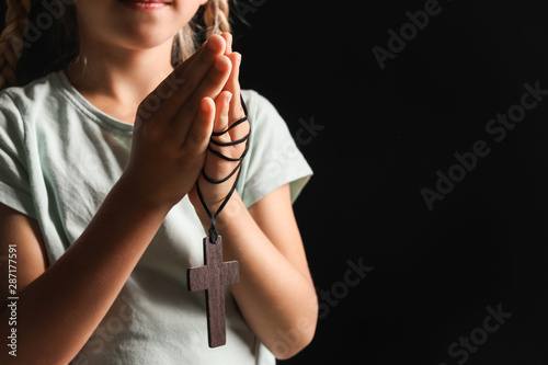 Little girl praying on dark...
