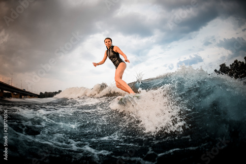 Girl riding on the wakeboard on the river on the wave on the bending knees