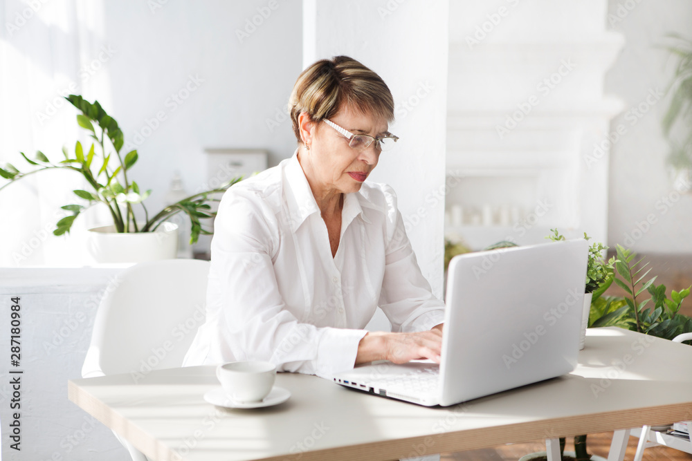 Attractive aged businesswoman working laptop computer indoors. Attractive aged businesswoman working laptop computer indoors.