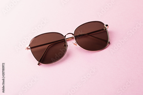Classic aviator mirrored flat lens sunglasses with golden metal frame closeup on pink background