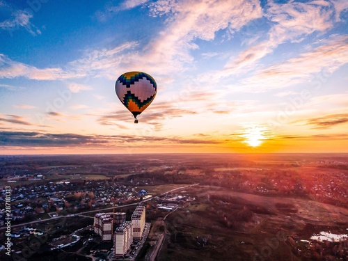 Aerial view of colorful hot air balloon is flying at sunset over the town in autumn season